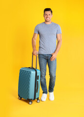 Poster - Handsome man with suitcase for summer trip on yellow background. Vacation travel