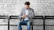 © fizkes - Confident man candidate applicant checking time, looking at wrist watch, waiting for job interview too long, sitting on chair in empty office hallway, recruitment and employment concept