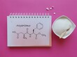 Structural chemical formula of aspartame molecule with artificial sweetener in bowl and white tablets. Aspartame is an artificial sweetener used as a sugar substitute in low-calorie food and drinks.