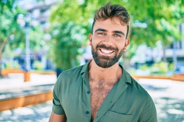 Young hispanic man smiling happy walking at the park