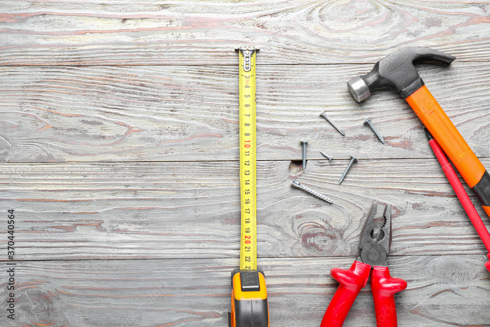 Measuring tape with builder's supplies on wooden background
