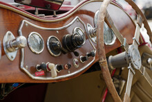 Selective Focus, Interior View Of Classic And Vintage Detail Of Gauge, Switches, Button, Meter And Wood Steering Wheel On Wooden Control Panel Dashboard Inside Old Antique Convertible Car.