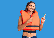 Young Handsome Man Wearing Nautical Lifejacket Smiling And Looking At The Camera Pointing With Two Hands And Fingers To The Side.