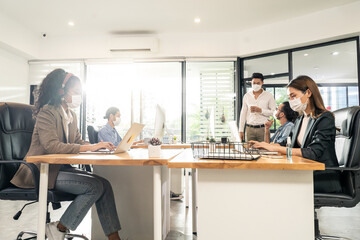 asian young business people wearing mask working on computer in office