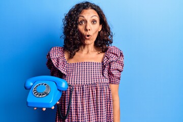 Sticker - Middle age beautiful woman holding vintage telephone scared and amazed with open mouth for surprise, disbelief face