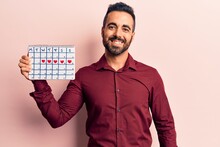 Young Hispanic Man Holding Heart Calendar Looking Positive And Happy Standing And Smiling With A Confident Smile Showing Teeth