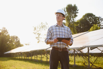 Solar power plant. Man standing near solar panels. Renewable energy.