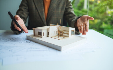 Wall Mural - A female architect working and showing an architecture house model with shop drawing paper in the office