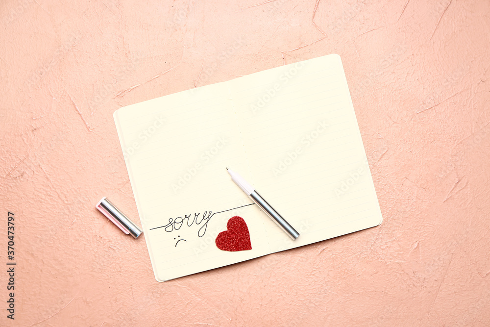 Notebook with written word SORRY on color background