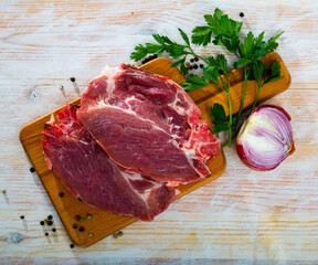 Raw meat, two fresh pork cutlets on wooden cutting board