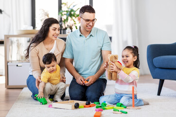 Wall Mural - family and people concept - happy mother, father, little daughter and baby son playing with wooden toys at home