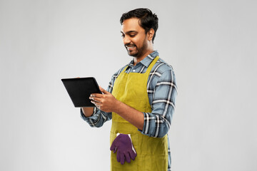 Poster - gardening, farming and technology concept - happy smiling indian male gardener or farmer in apron with tablet pc computer over grey background