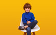 © kegfire - Positive boy in casual clothes sitting on chair