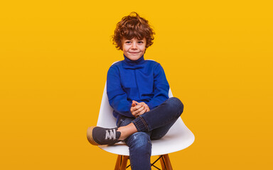 positive boy in casual clothes sitting on chair