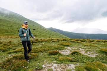hiking and recreation in mountains. a guy with a nordic walking poles walks with a scenic landscape 