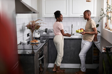 beautiful young black african couple have conversation in the kitchen, they cook together, preparing food as one team. friendly family concept