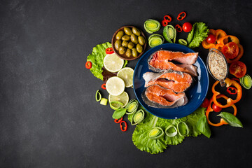 Raw steak trout, fresh tomatoes, peppers, olives, garlic on a black background,. Organic and fresh food concept/