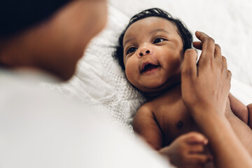 Portrait of enjoy happy love family african american mother playing with adorable little african american baby.Mom touching with cute son moments good time in a white bedroom.Love of black family 