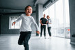© standret - Woman in formal clothes and with camera in hand standing inside of empty room with man and little boy that running and having fun