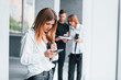 © standret - Girl with phone standing against woman in formal clothes that with camera in hand standing inside of empty room with man