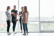 © standret - Woman holding her professional camera. Group of business people in formal clothes standing indoors near big window