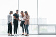 © standret - Woman holding her professional camera. Group of business people in formal clothes standing indoors near big window