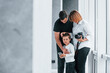 © standret - Woman in formal clothes and with camera in hand standing inside of empty room with man and little boy