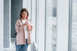 © standret - Young girl in casual clothes standing indoors with her phone in hand