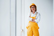 © standret - Female worker or engineer in yellow uniform and hard hat standing indoors