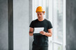 © standret - Male worker or engineer in yellow hard hat standing indoors with notepad