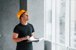 © standret - Male worker or engineer in yellow hard hat standing indoors with notepad