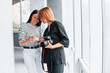 © standret - Two women standing indoors with camera and phone in hands