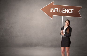 Young business person in casual holding road sign with INFLUENCE inscription, business direction concept