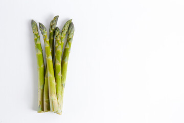 Wall Mural - Bunch of raw asparagus stems isolated on white. Edible Asparagus Officinalis sprouts laid on paper textured background. Close up, copy space, top view, flat lay.