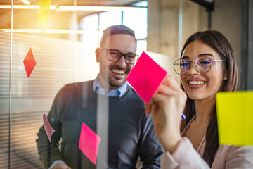 Multi-ethnic group trendy business people discussing during a brainstorm session for their small company. Cropped shot of a group of young designers using sticky notes during a brainstorming session