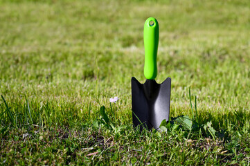 Garden scoop with green handle on the grass. Gardening tools.