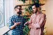 © BullRun - Cheerful male coach in casual wear explaining information to young employee smiling and gesturing during communication, positive hipster guy telling funny story to best friend in coworking office.