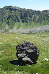 Huge dark rock stone on the background of a mountain valley