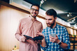 © BullRun - Portrait of cheerful handsome male looking at camera holding notepad with planning for job, hipster guy pointing on notes of colleague cooperating on common project in friendly atmosphere together