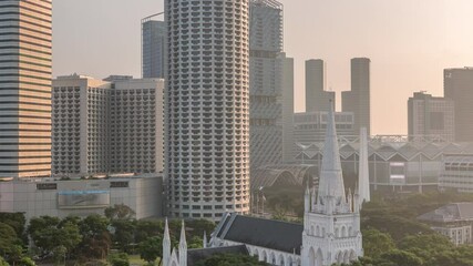 Wall Mural - St. Andrew's Cathedral aerial timelapse early morning after sunrise. It is an Anglican cathedral in Singapore, the country's largest cathedral. Skyscrapers on a background