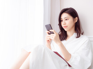 Wall Mural - Young asian woman using smartphone at home