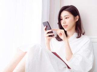 Wall Mural - Young asian woman using smartphone at home