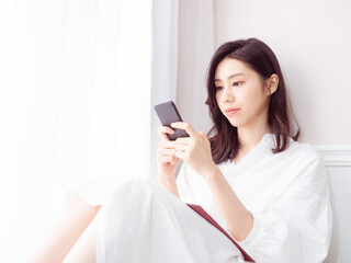 Wall Mural - Young asian woman using smartphone at home