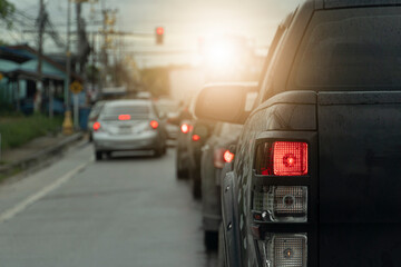 Rear side of black pickup car open brake light on the road.  Blurry image of other cars with red traffic lights.