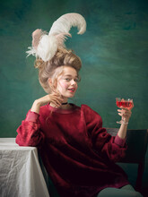 Alcohol Cocktail Time. Young Woman As Marie Antoinette On Dark Green Background. Retro Style, Comparison Of Eras Concept. Beautiful Female Model Like Classic Historical Character, Old-fashioned.