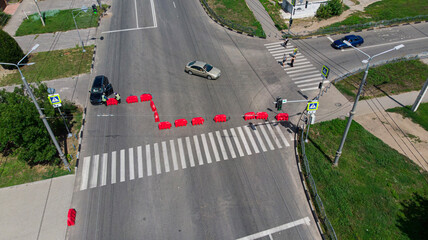 Aerial. Detour background. Closed road with plastic fence. Pedestrian crossing with people. View above.