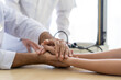© amorn - Senior male doctor holding hand and comforting patient young woman at consulting room. Healthy and psychology concept.