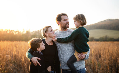 Beautiful young family with small children on a walk in autumn nature.