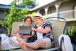 © Halfpoint - Senior couple with tablet outdoors on holiday, relaxing.