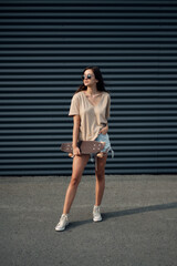 Young Woman With Longboard. Girl skater posing on longboard in sunny weather